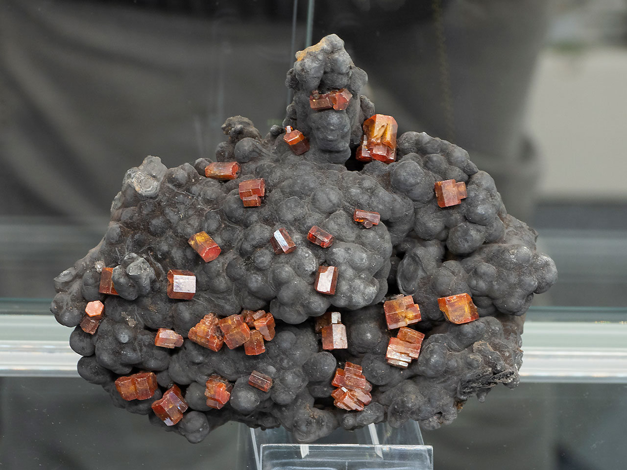 Bright orange-red vanadinite on dark coronadite from Taouz, Morocco