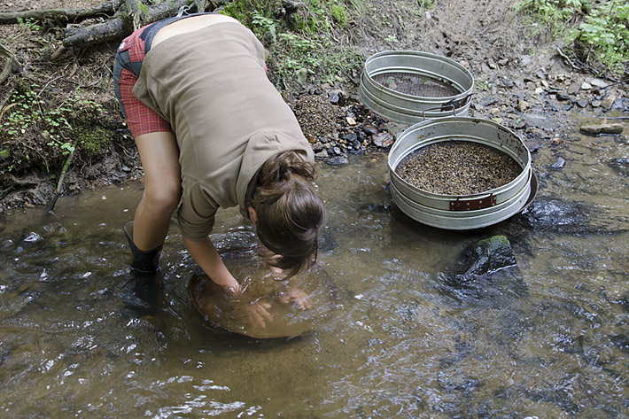 Young lady gold panning in the small creek