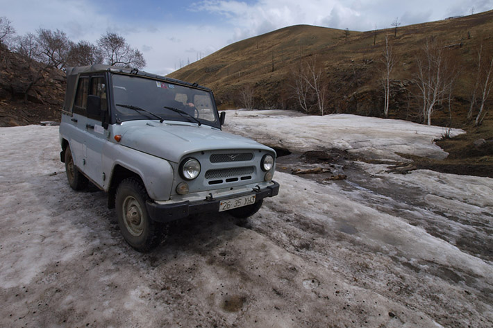 Crossing frozen river with offroad vehicle in the early spring